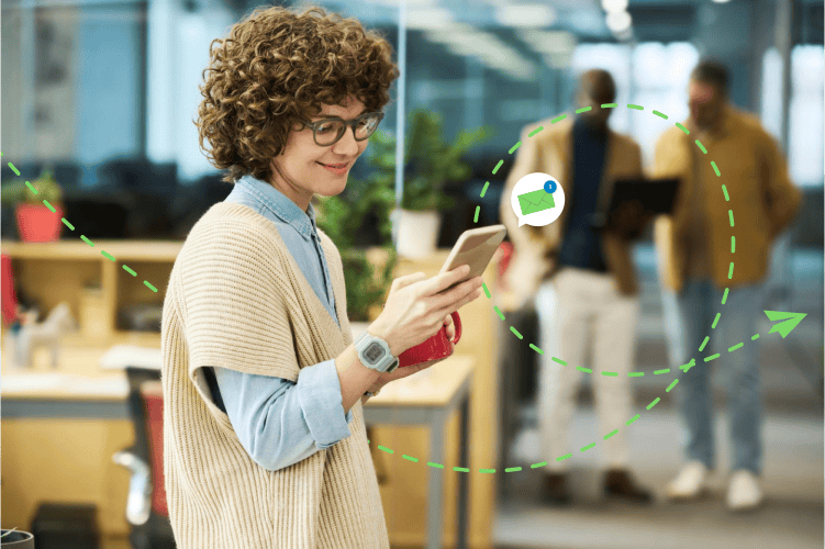 Woman standing in office, learning on smartphone while taking a coffee break